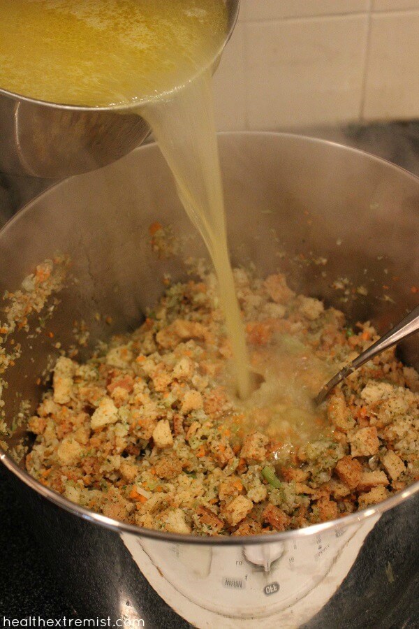 Making Paleo Stuffing - Pouring mixture of butter and vegetable broth over paleo stuffing bread cubes.