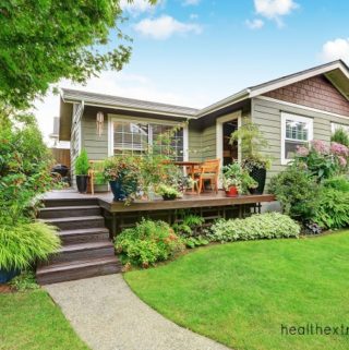 House with backyard and deck with potted plants and planted plants